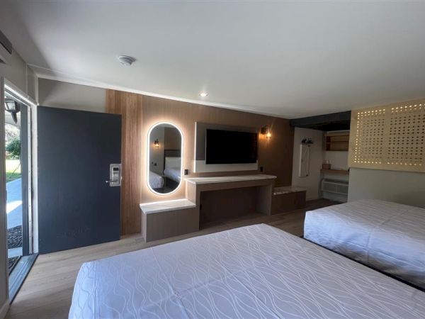 A modern hotel room with two beds, a TV, and an open door bringing in natural light ends the sentence.